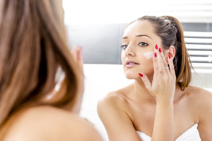 woman applying moisturizer to her face