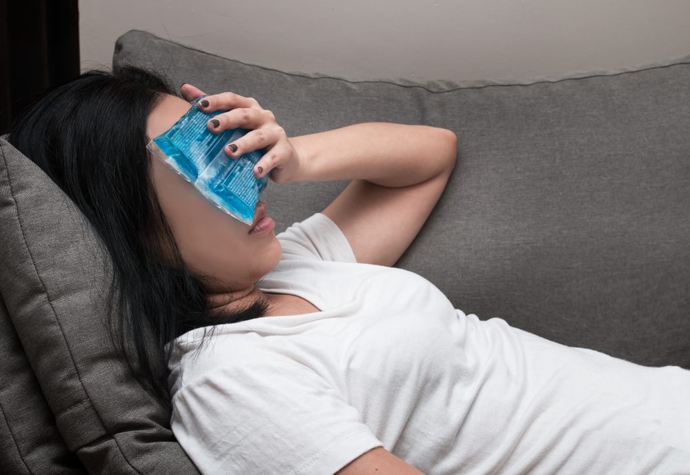 Asian woman with ice cold pack on her forehead for relief fever headaches and migraines