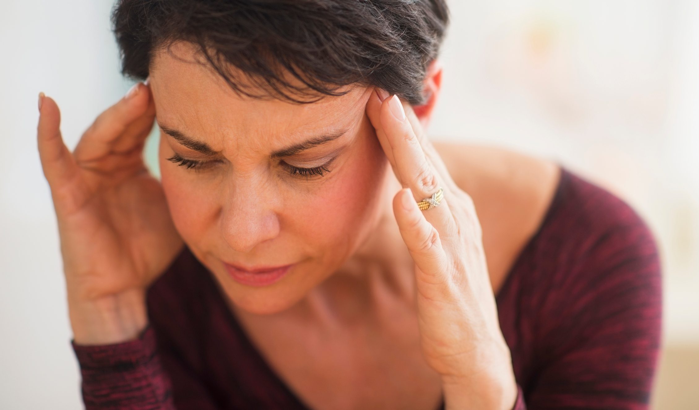 close up of woman with hands on forehead stressed trying to remember