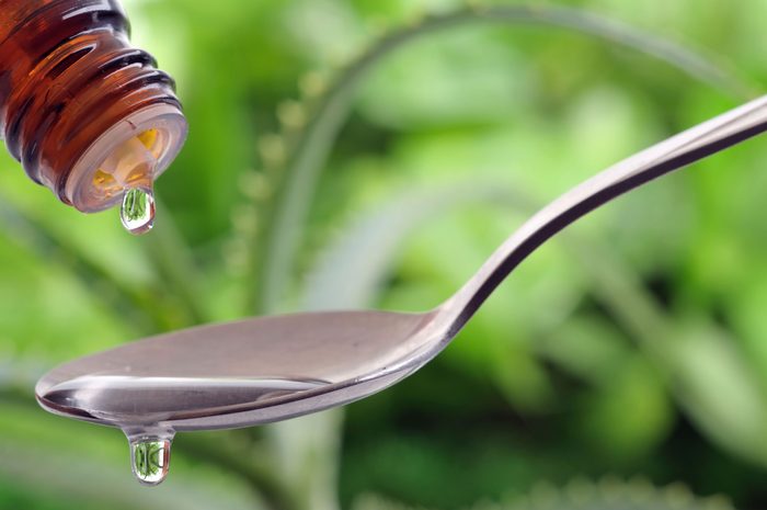 essential oil dripping from a bottle into a spoon