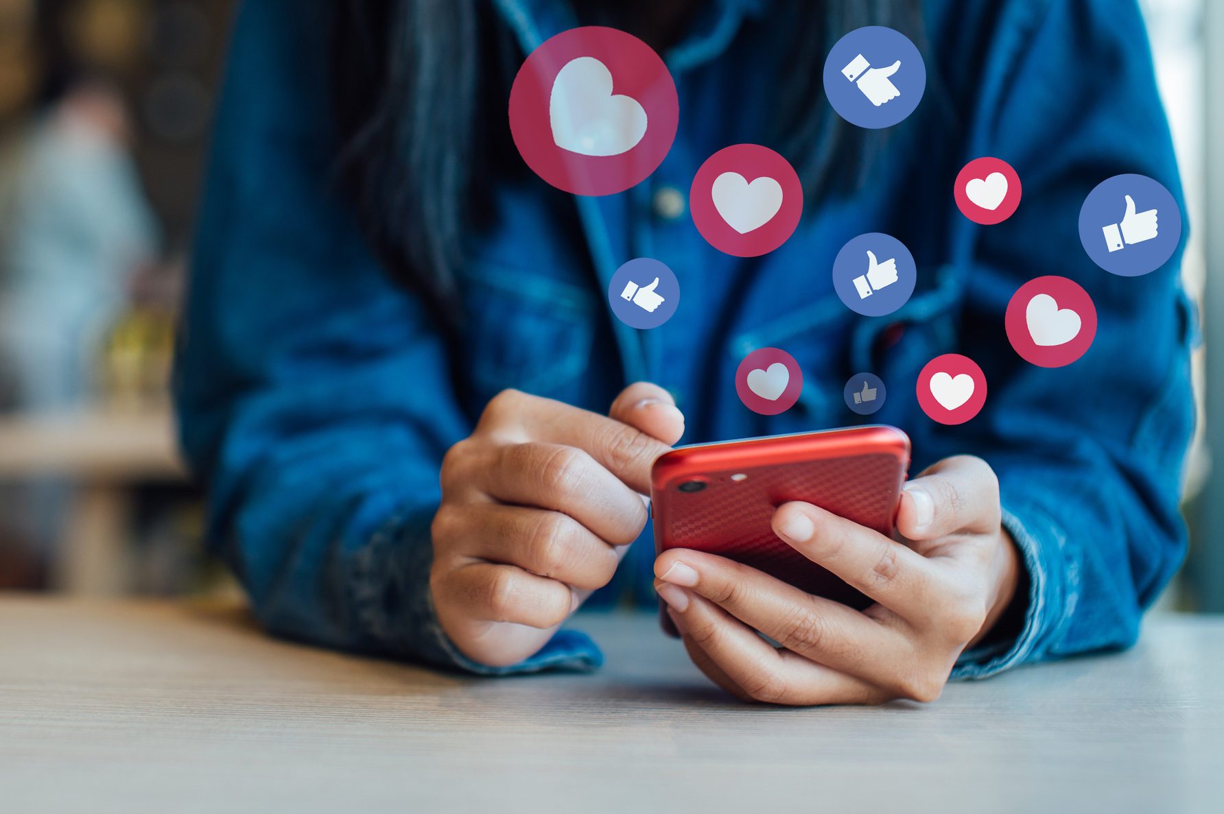 close up of smartphone in person's hands with likes and heart bubbles