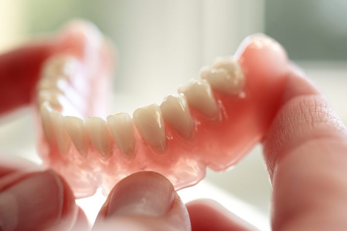 hands holding bottom dentures