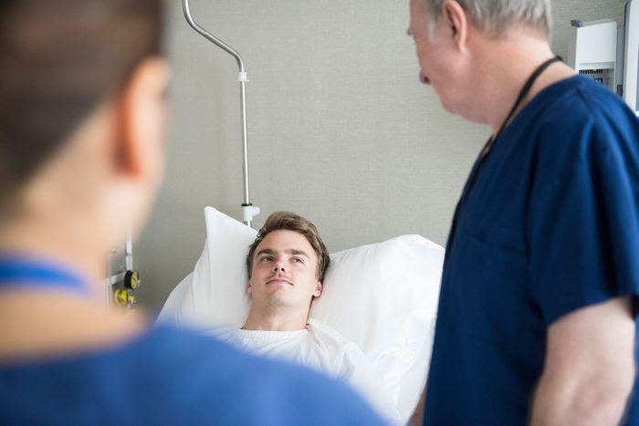 hospital patient in bed talking to healthcare workers