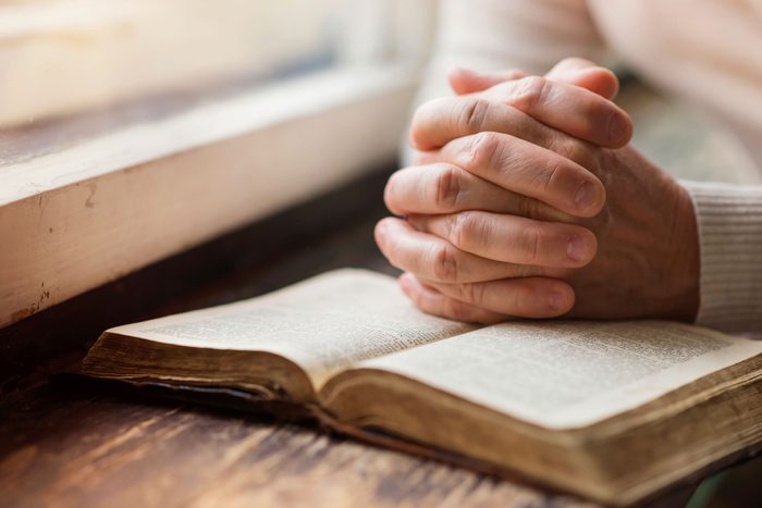 hands clasped over book