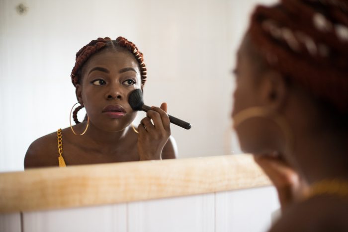 woman applying makeup to face
