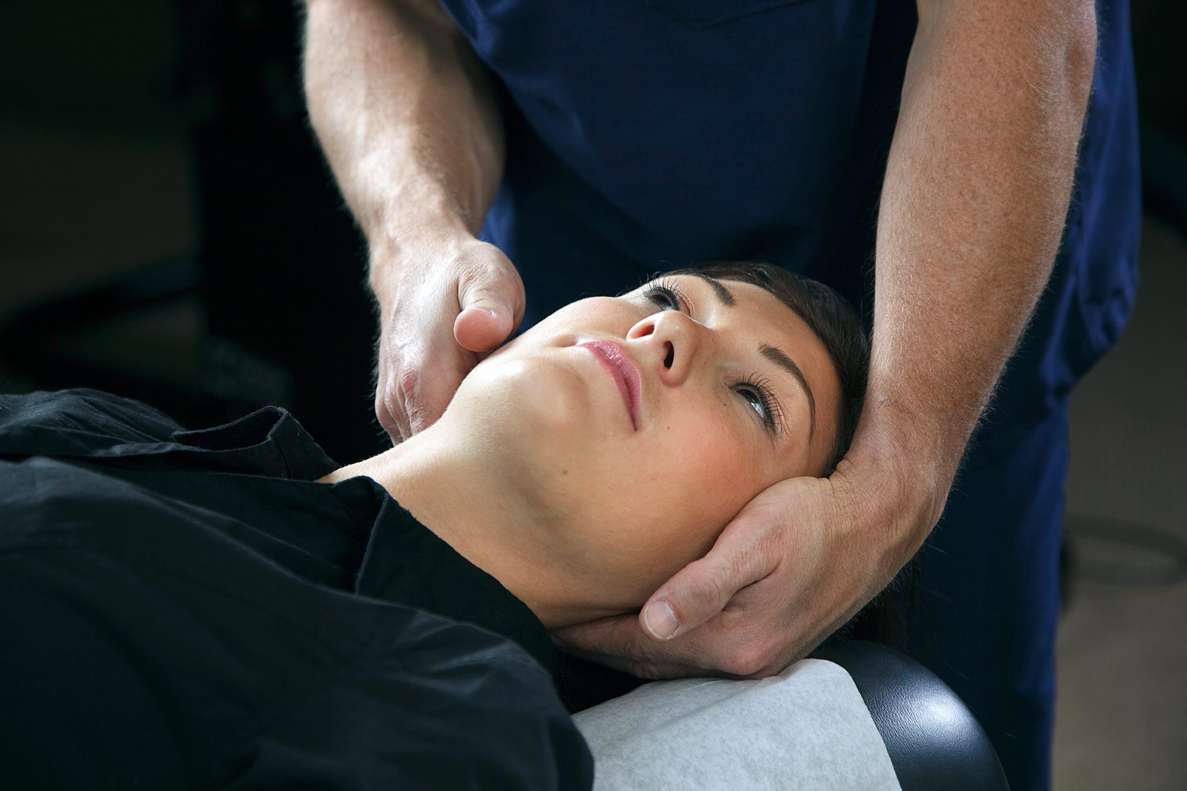 a man's hands manipulating a person's head and neck