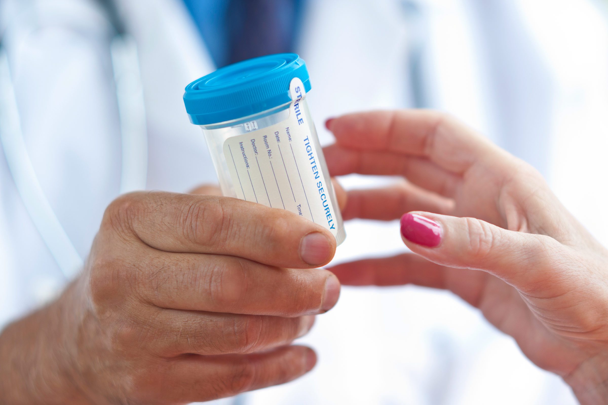 doctor passing a patient a collection bottle