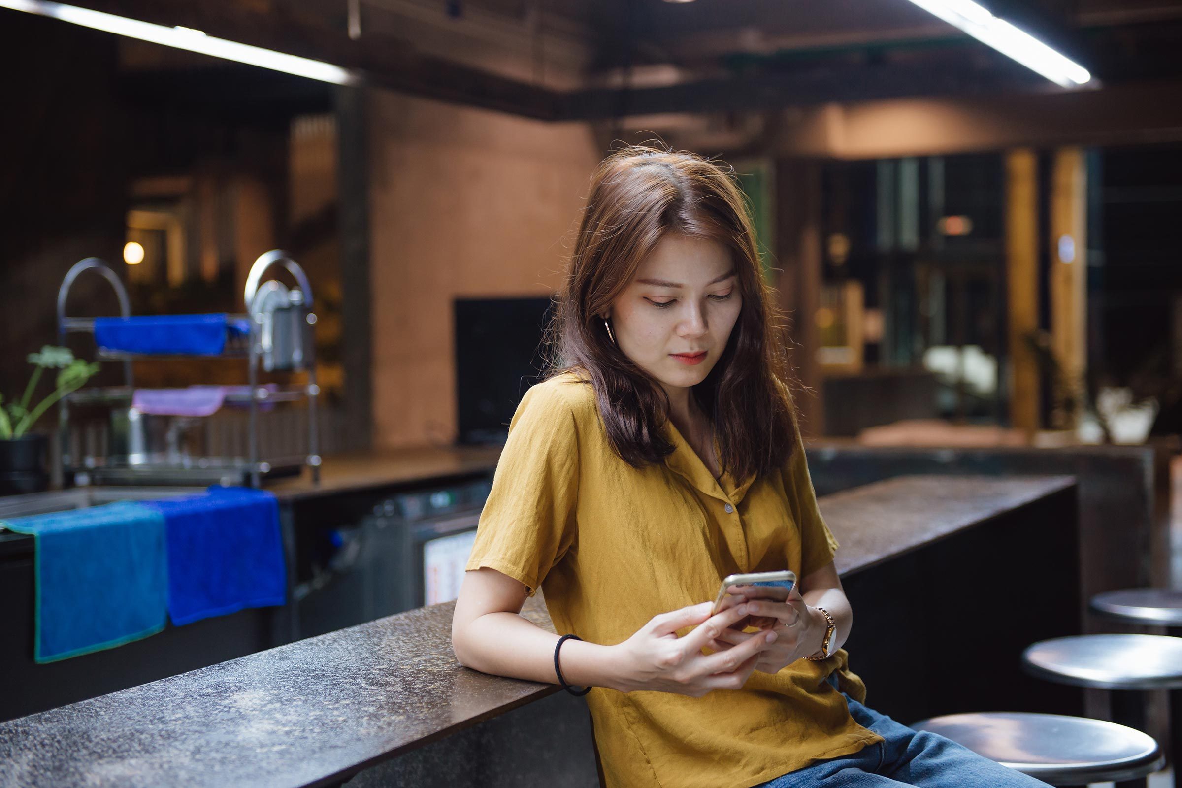 woman alone at bar checking phone