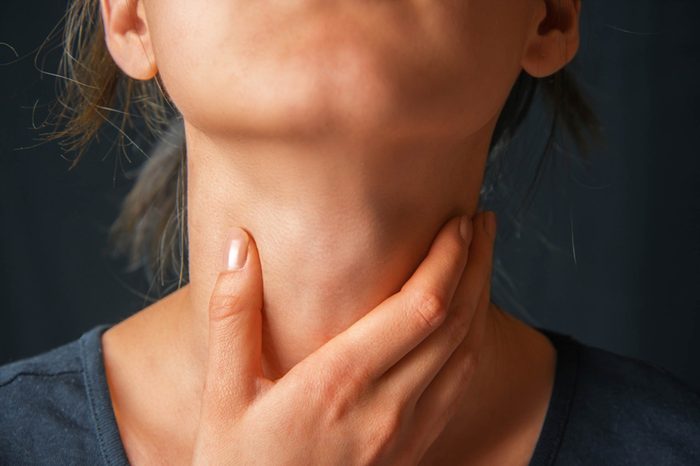 Woman feeling her neck.