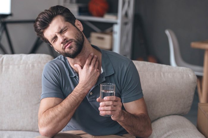 Man feeling his throat.