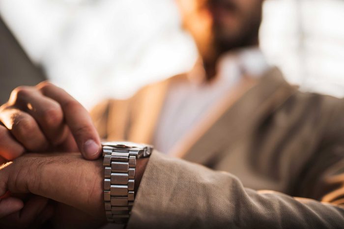 Man looking at a silver watch on his wrist.