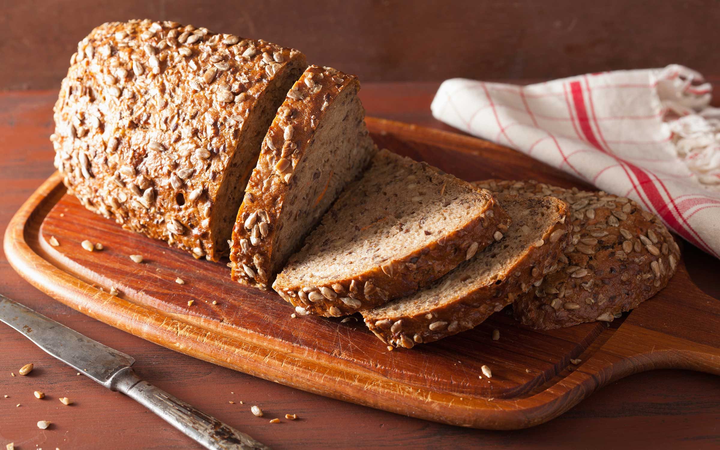 half-sliced broad bread on wooden board 