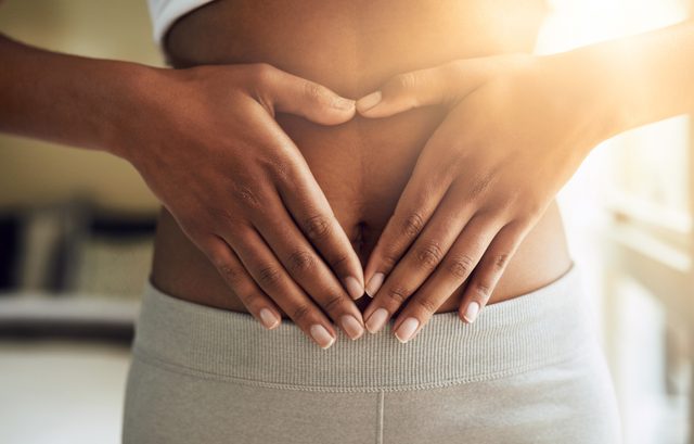 woman with hands on lower stomach; digestion concept
