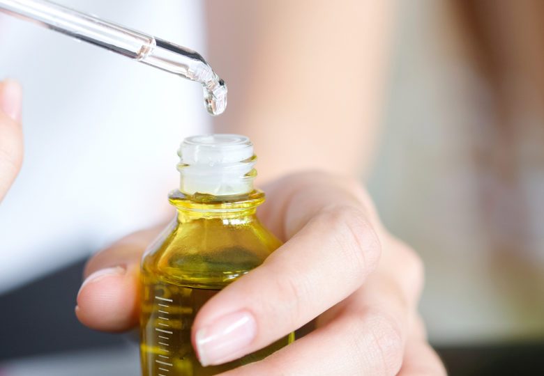 hands of a beautiful woman Dropping serum collagen moisturizer of face into clear yellow bottle soft light background. Protector skin Treatment facial essence oil, Vitamin C. Beauty and spa Con