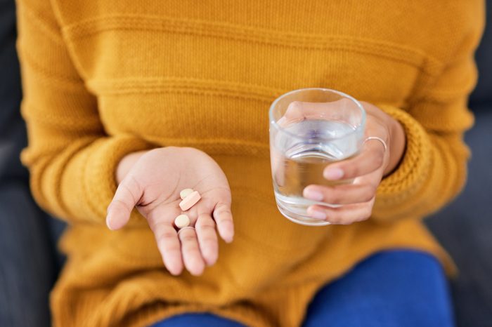 close up of woman holding a glass of water and medication