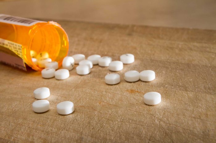 Pill bottle with pills spilling onto the floor.