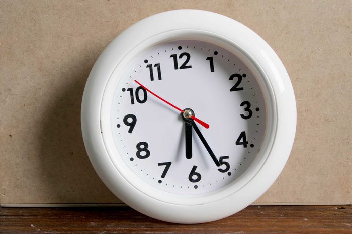 White clock resting on a hardwood floor.