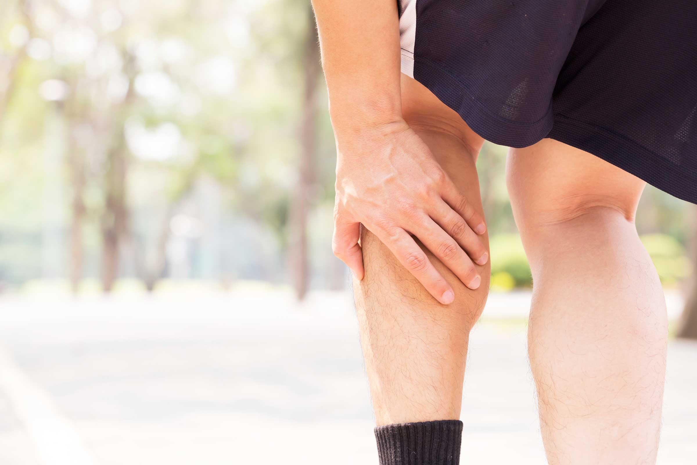 Exercising man holding his calf