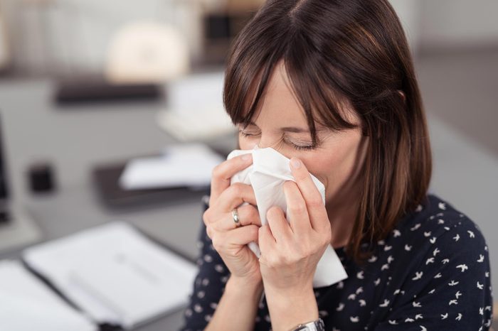 woman sneezing into a tissue
