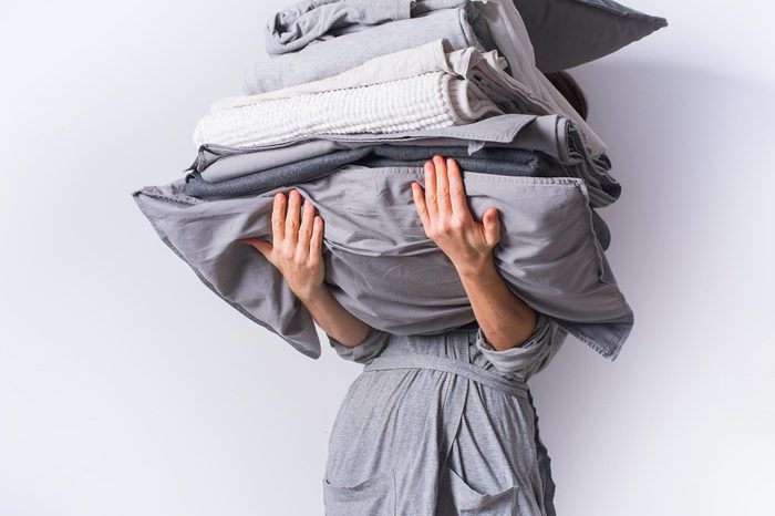 woman holding a stack of bedding