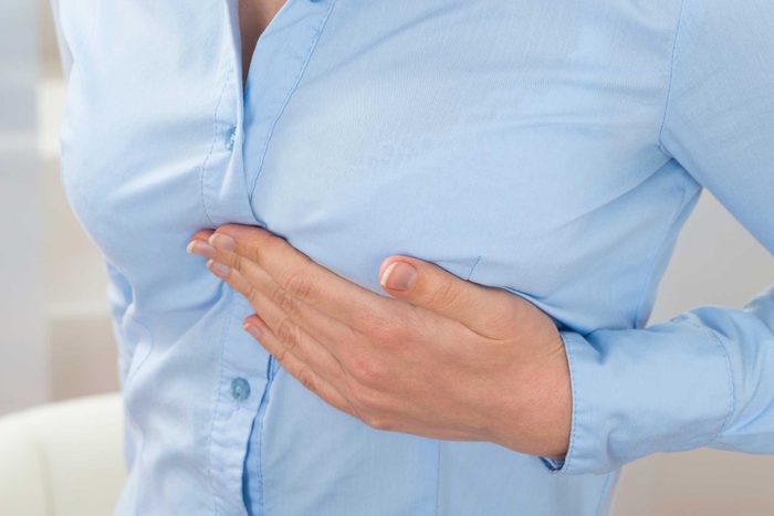 woman in a blue shirt holding her breast
