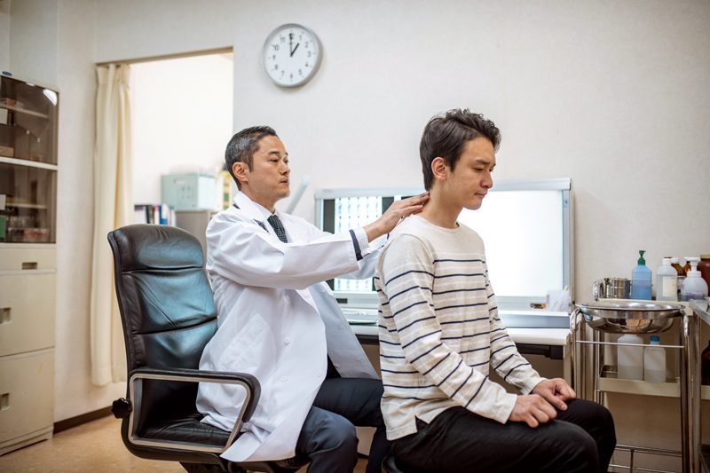 chiropractor examining patient's neck and back