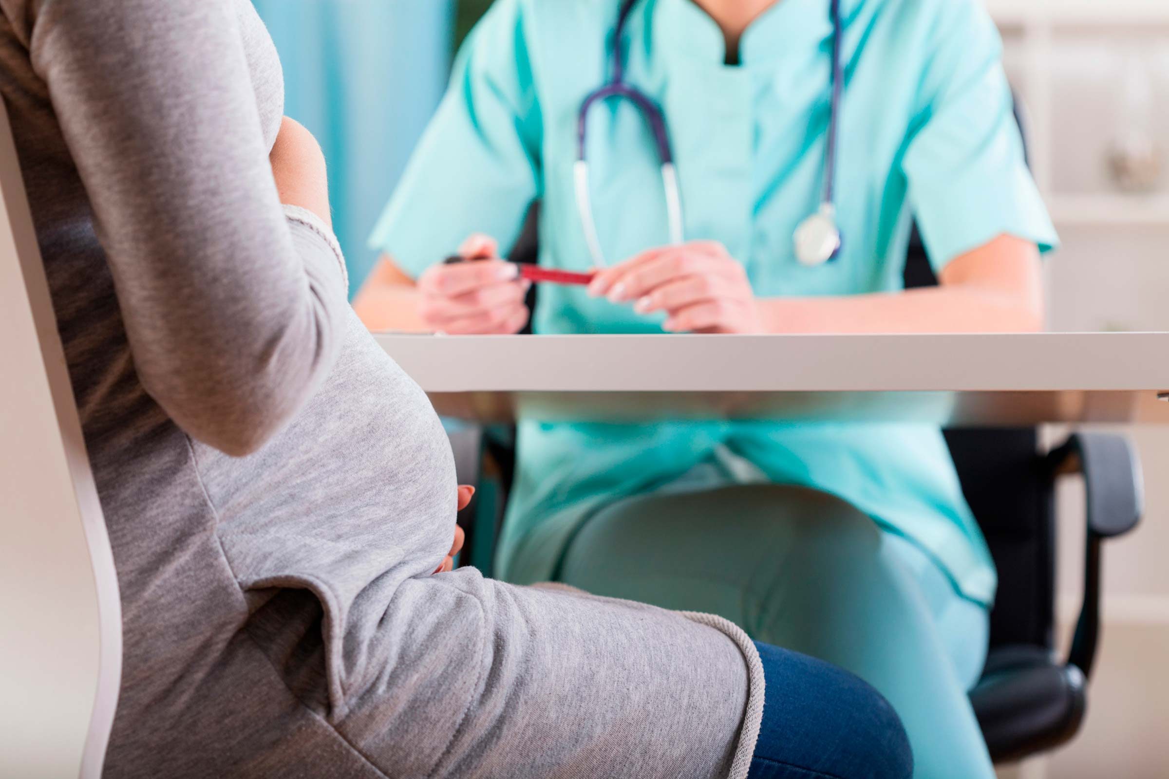doctor speaking to pregnant woman, seated at table