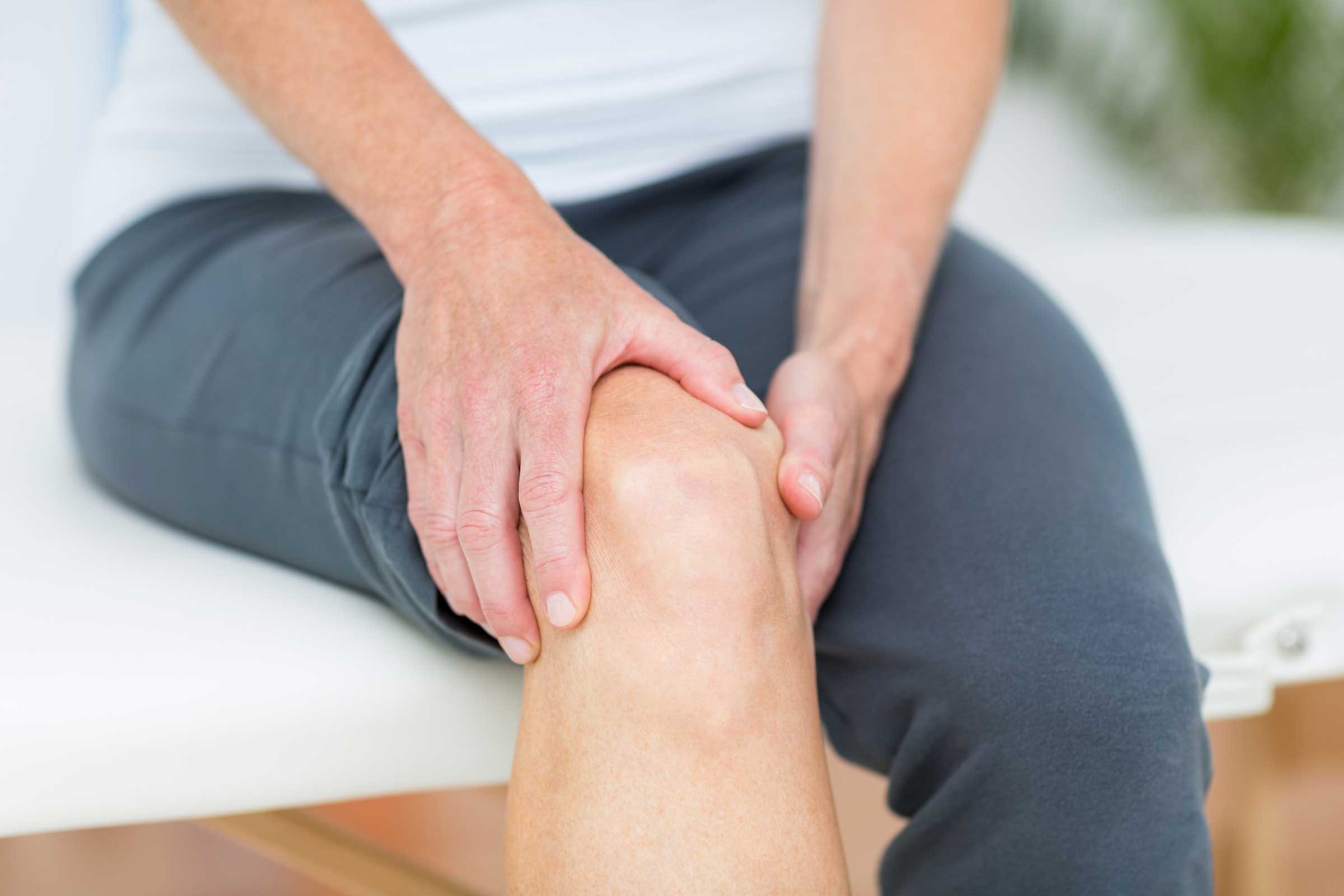 Man holding his knee as if having knee pain.