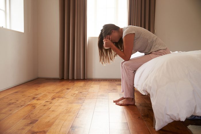 young woman crying in bed