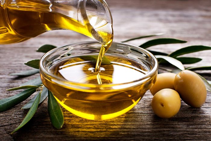 olive oil pouring from a carafe into glass bowl