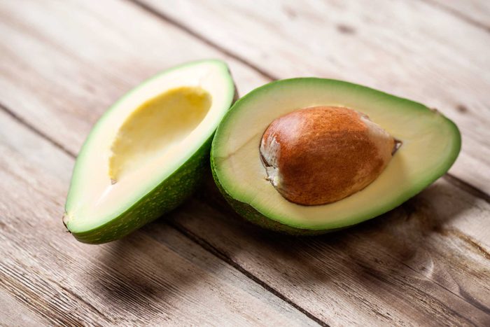 avocado cut in half on wood surface