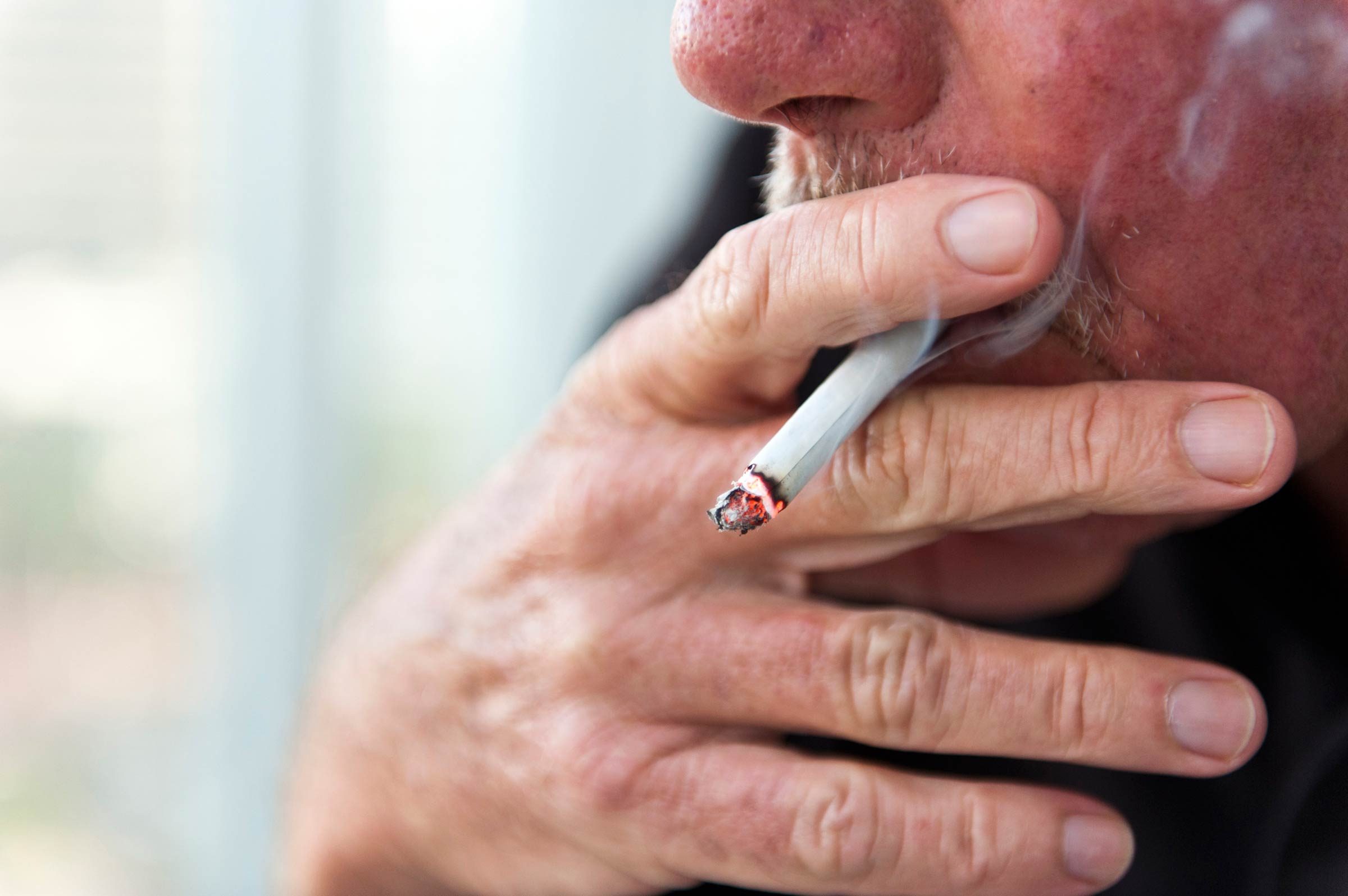 Man with a mustache smoking a cigarette.