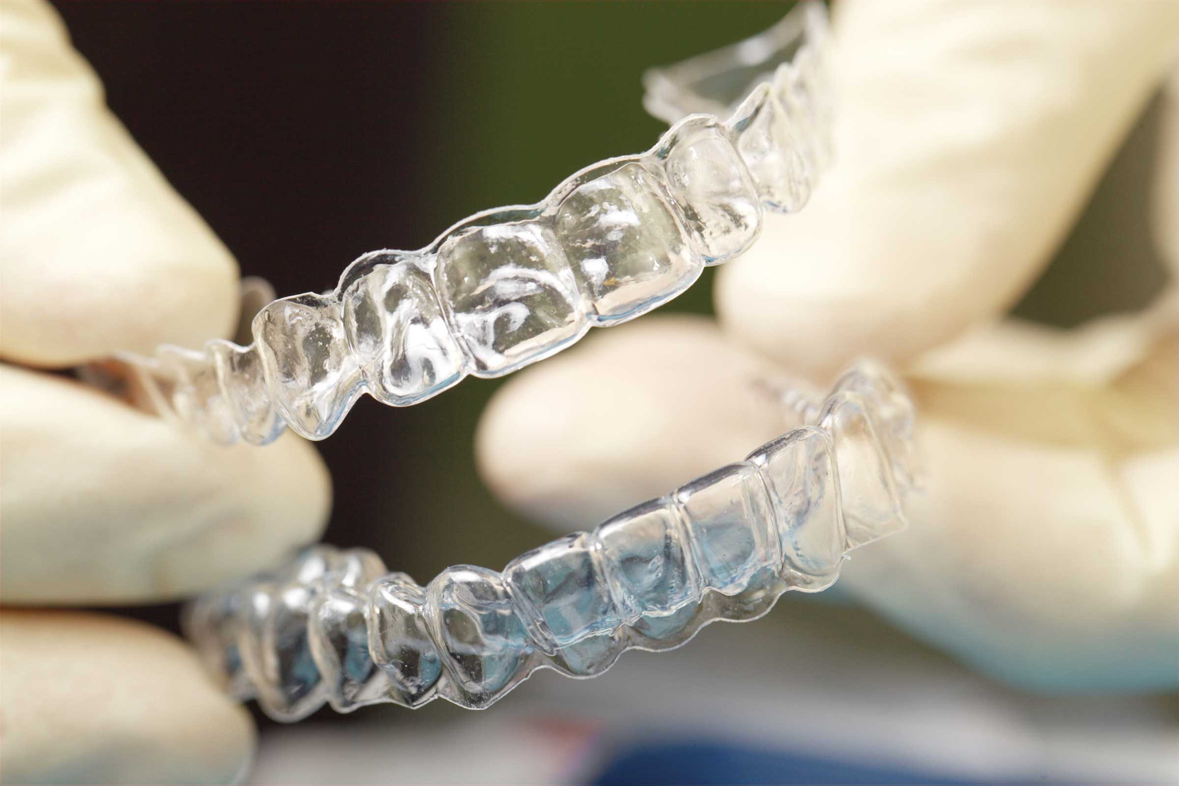 gloved hands holding a mouth guard