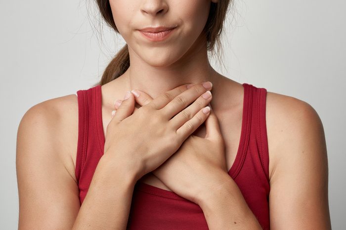 woman holding both hands to her throat