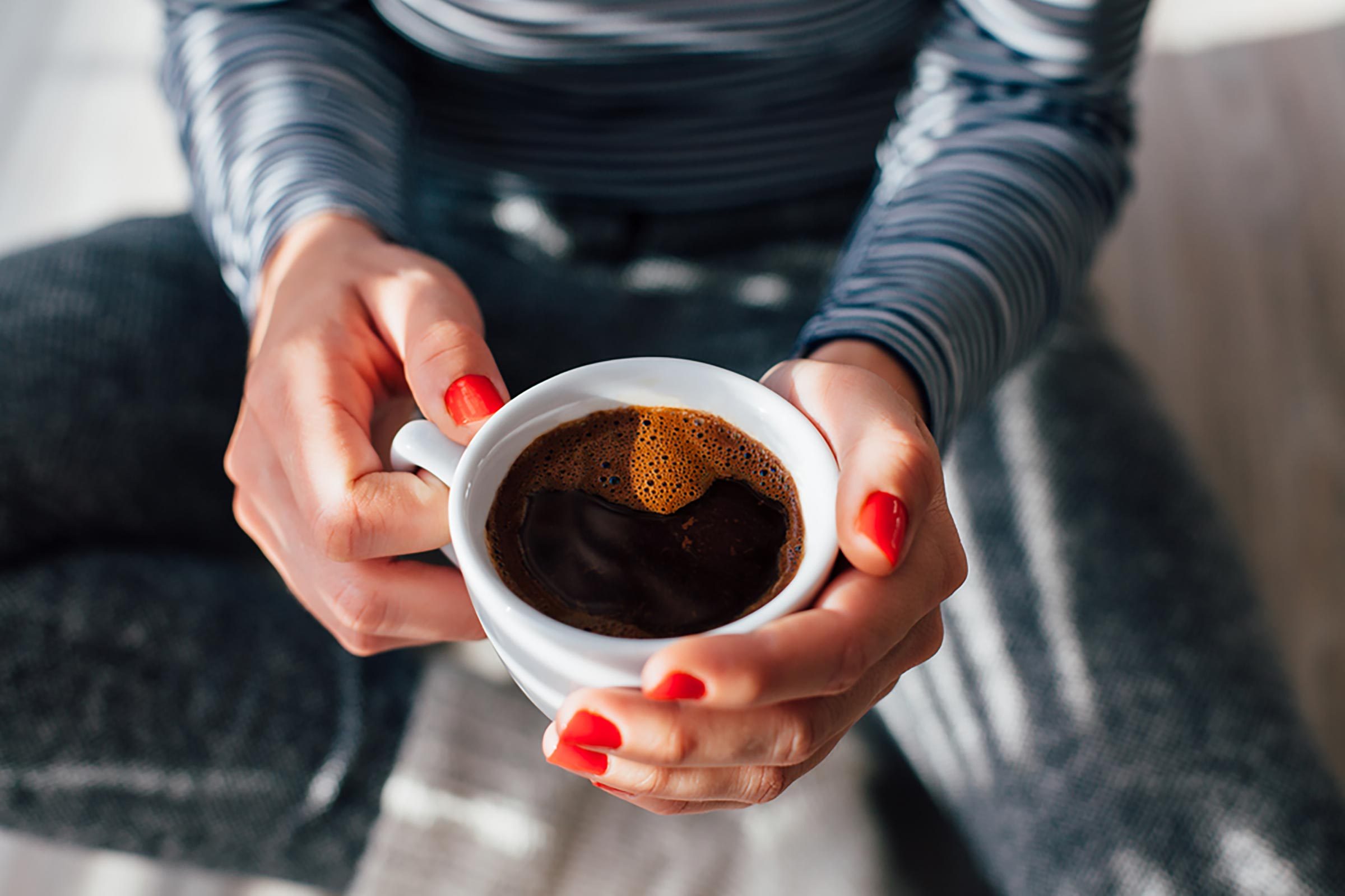woman's hands, holding cup of coffee