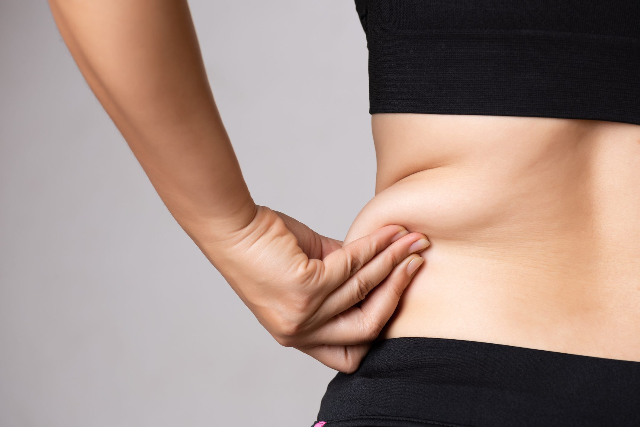 woman grabbing excess fat on side of her stomach and back