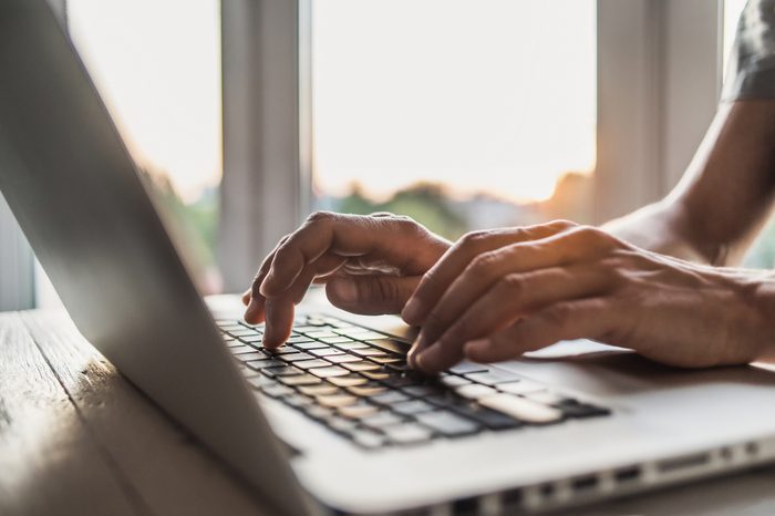 close up of hands typing on laptop keys