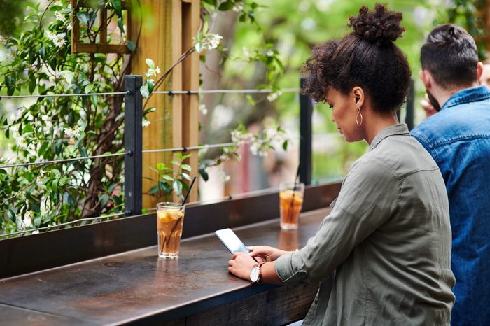 woman sitting at a bar using her phone