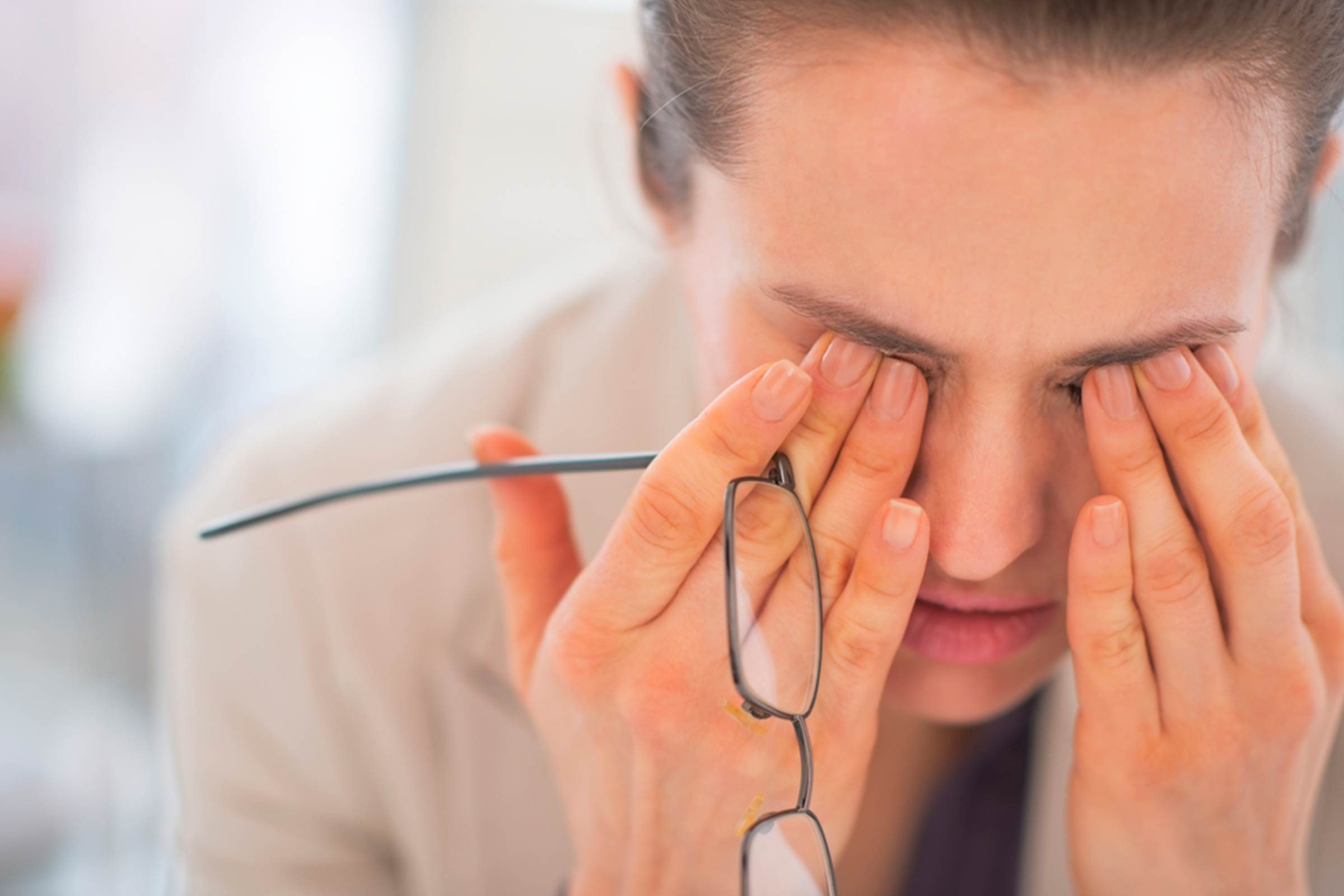woman leaning forward and rubbing her eyes