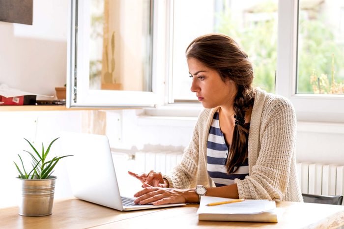 A woman with brown hair working on a laptop.