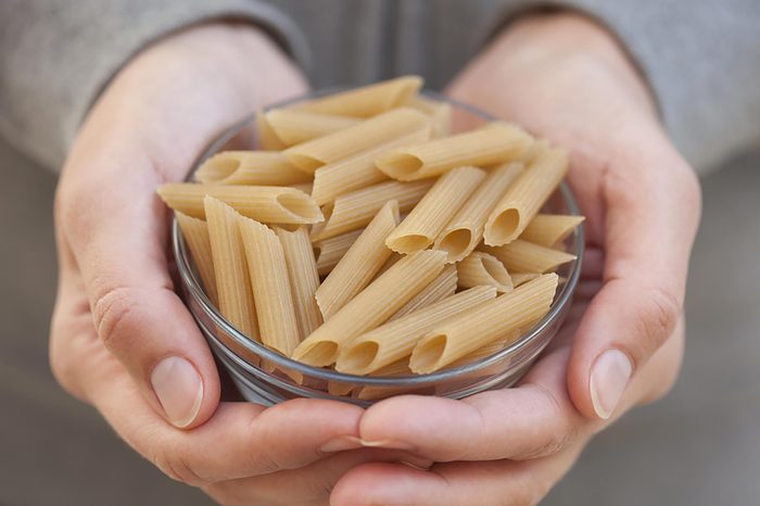 Person holding a bowl of brown rice noodles.
