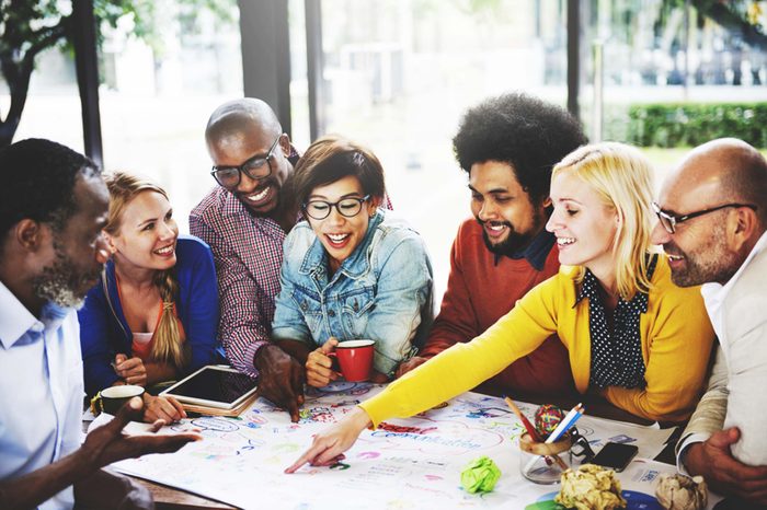Group sitting at table over project plans