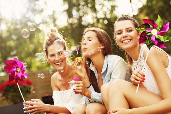 Three girlfriends with pinwheels and blowing bubbles