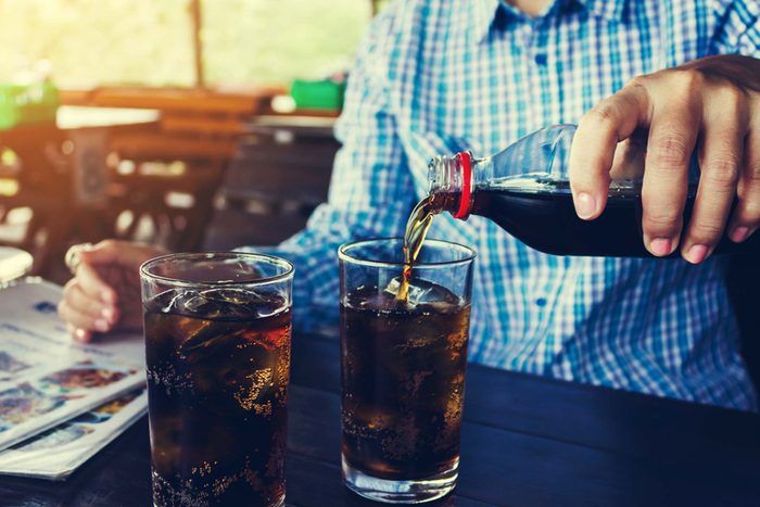 anonymous man pouring soda into a glass