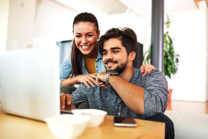 couple smiling while looking at cat videos on a laptop