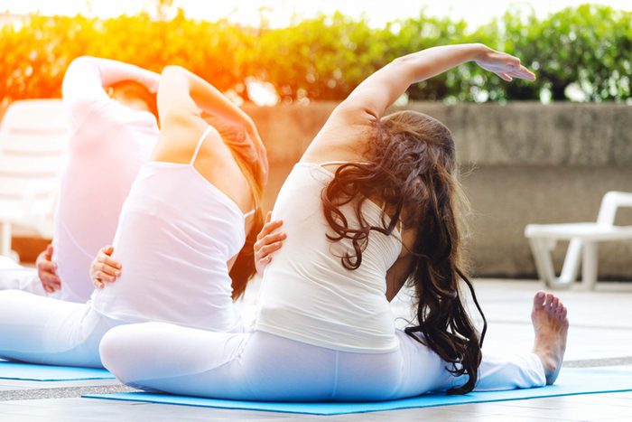 three anonymous people side bend during a yoga class
