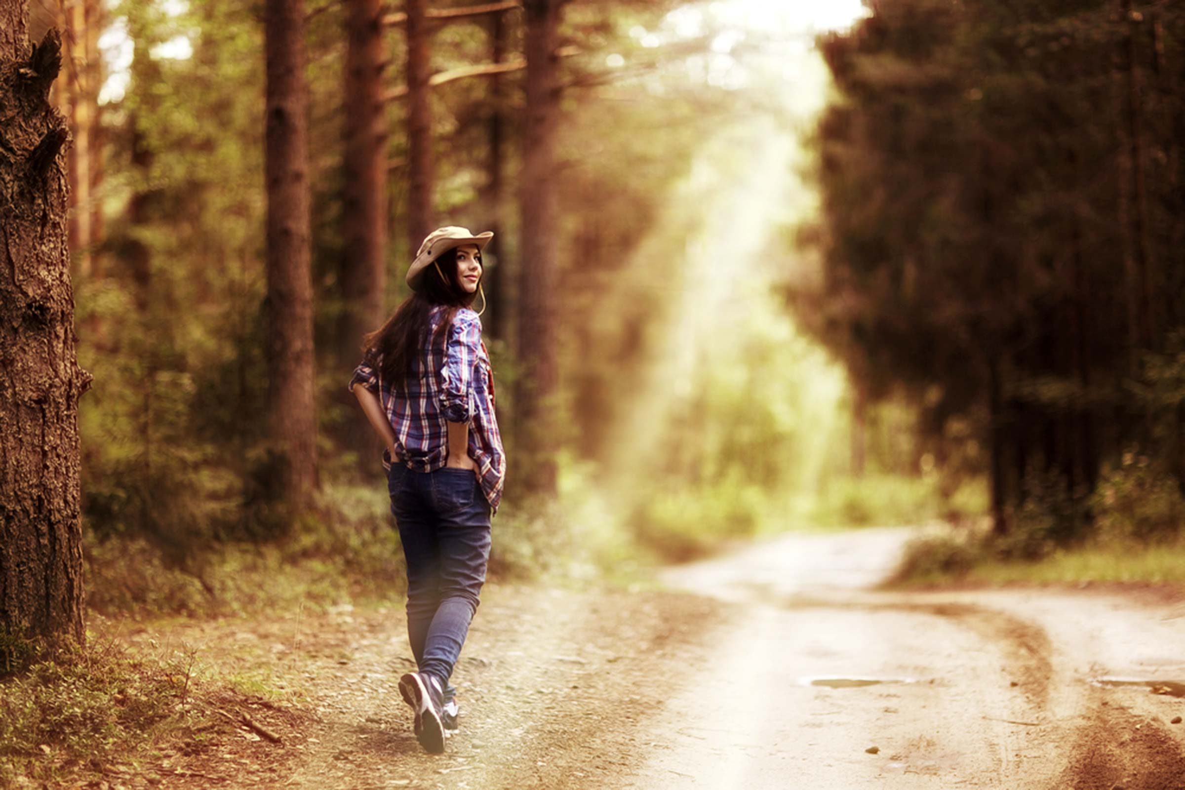 Woman dressed in hat, long sleeves, and pants in a forest