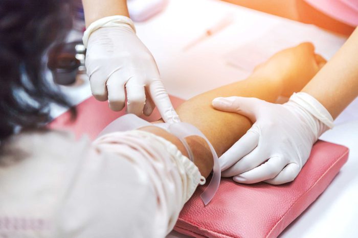 gloved nurses hands taking a patient's blood from the arm
