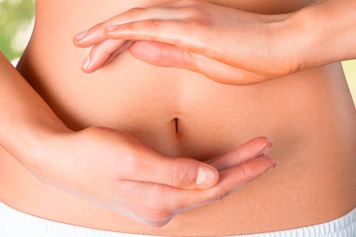 woman holding her ands above and below her bare belly button