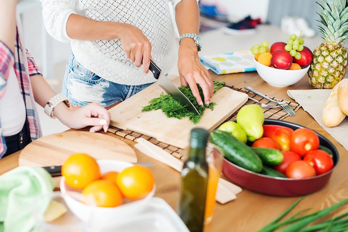 woman chopping herbs on a cutting board